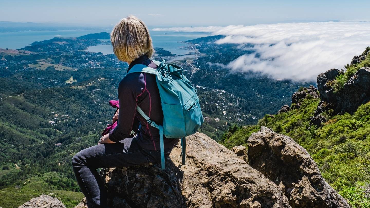 Woman wearing backpack overlooking Pacific Ocean
