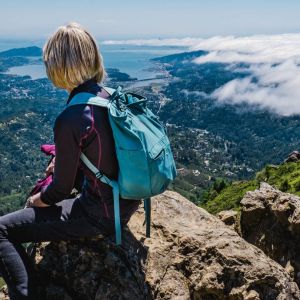 Woman wearing backpack overlooking Pacific Ocean