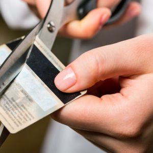 Person cutting credit card in half with scissors