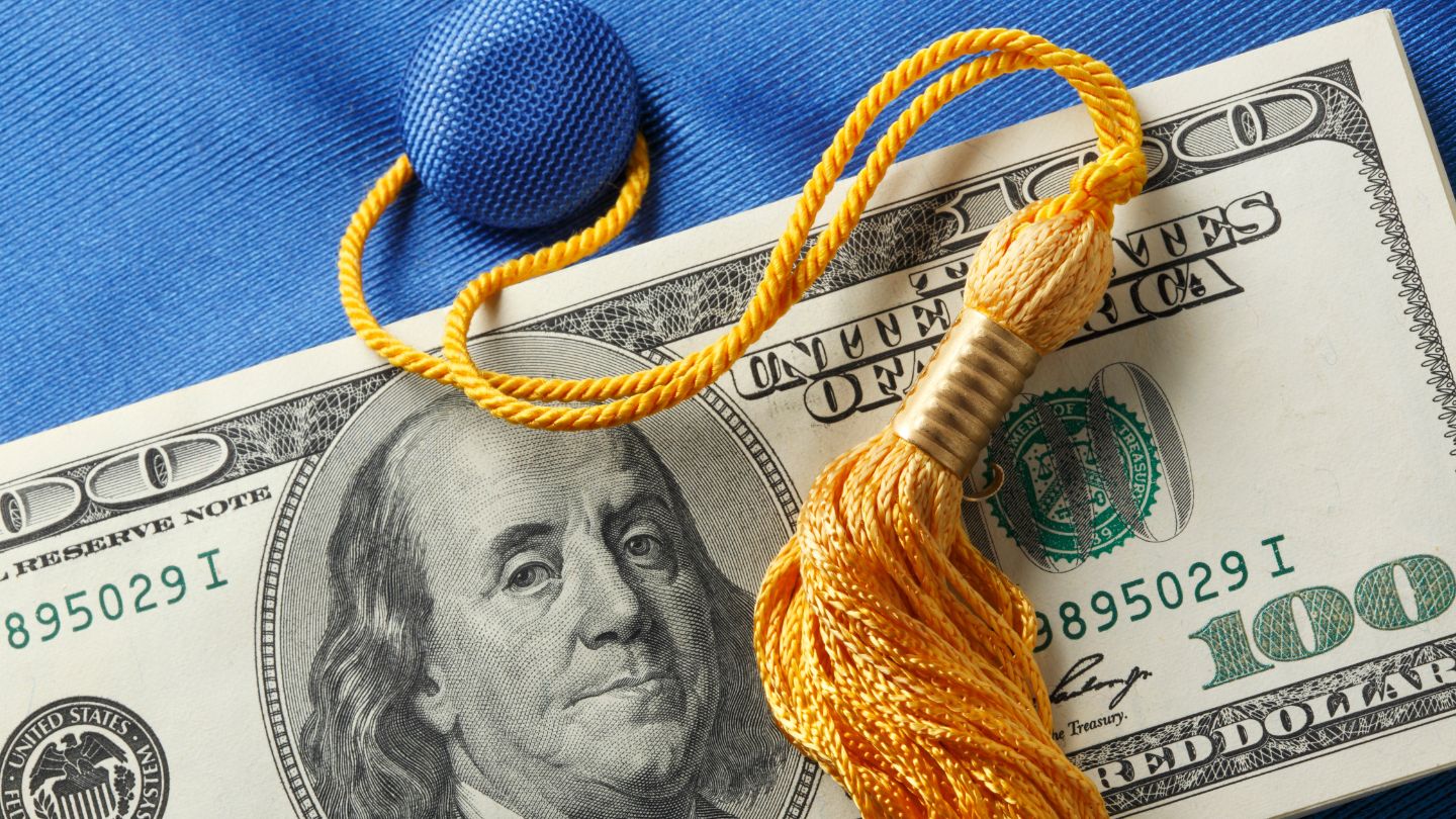 Image of a $100 American bill and a graduation cap with tassel.